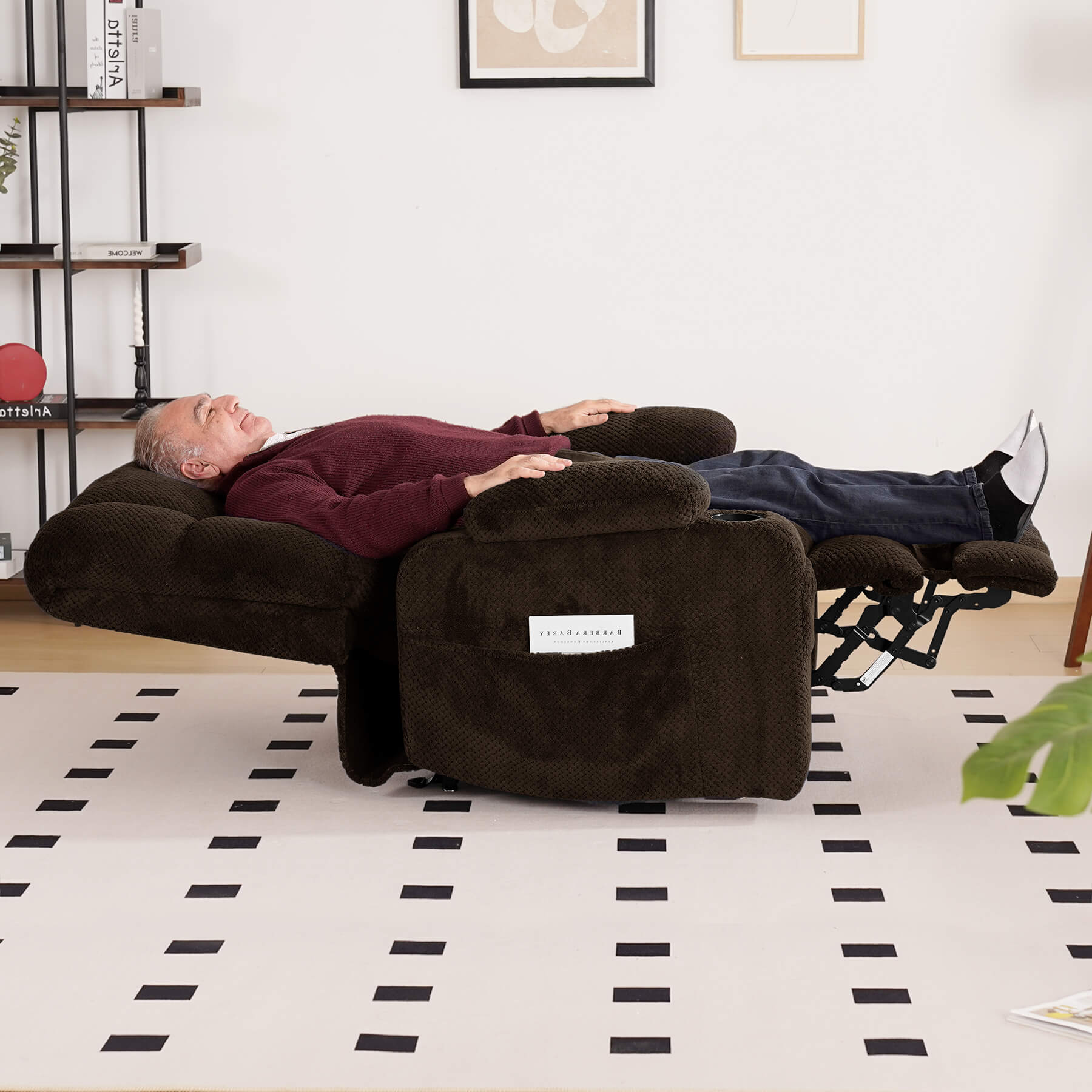 An elderly person is sleeping on a brown lie-flat recliner in the living room.