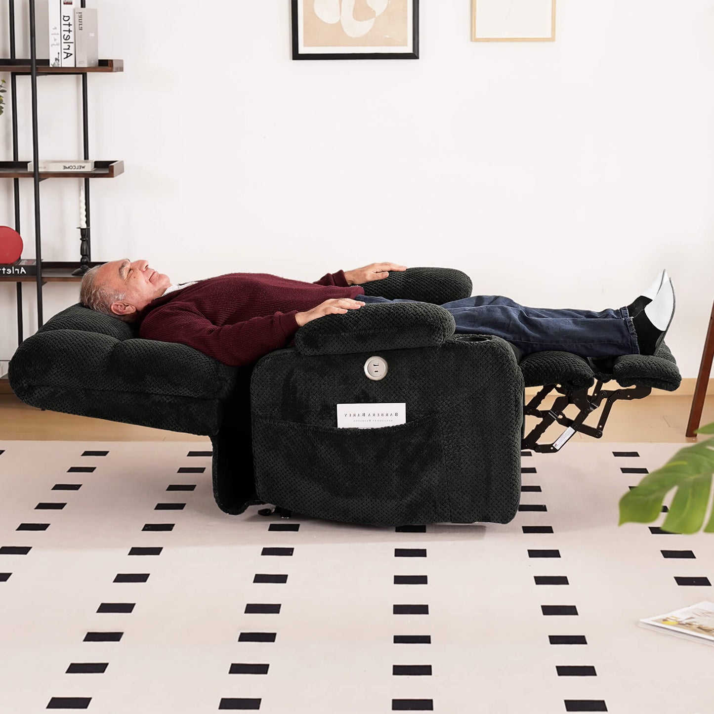 An elderly person is sleeping on a gray lie-flat recliner in the living room.