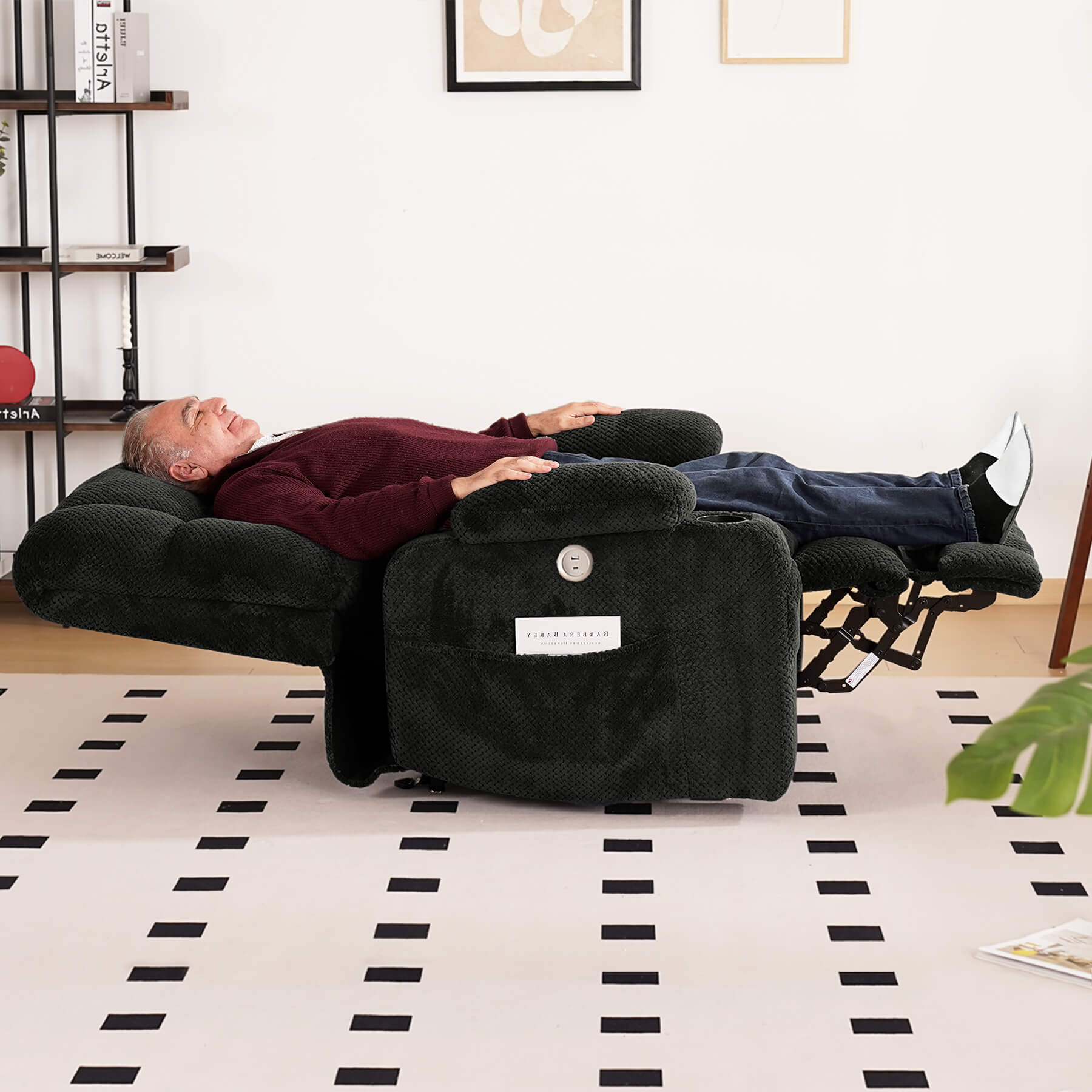 An elderly person is sleeping on a gray lie-flat recliner in the living room.